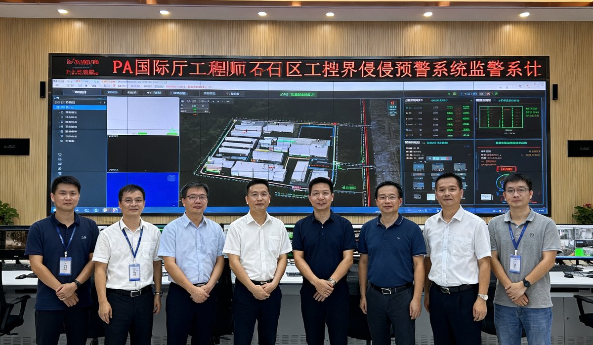 惠州大亚湾石化园区安防升级项目验收现场照片，PA国际厅工程师团队与园区管理人员在监控中心合影，背景大屏展示周界入侵预警系统运行界面